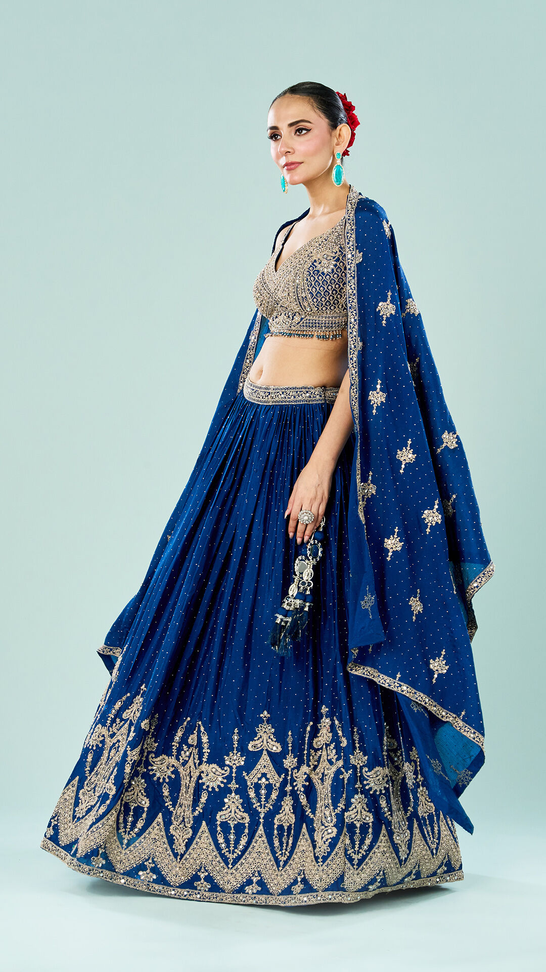 Bride in royal blue lehenga with intricate golden embroidery and mirror work, paired with heavily embellished blouse and embroidered dupatta